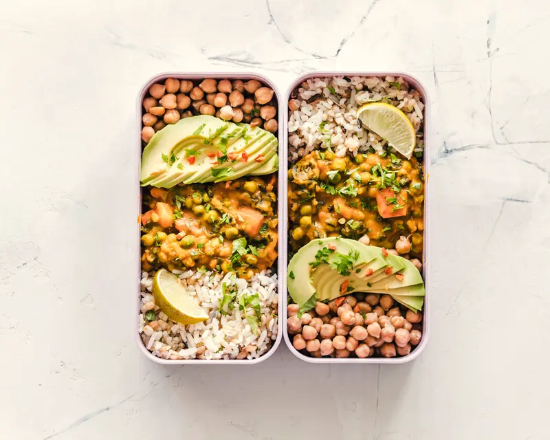 Due contenitori con riso, ceci, verdure e avocado