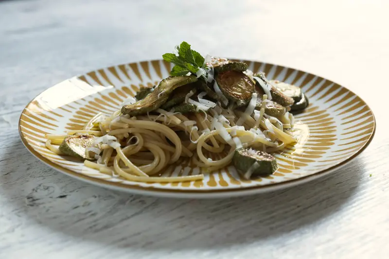 Piatto di spaghetti con zucchine e scaglie di formaggio