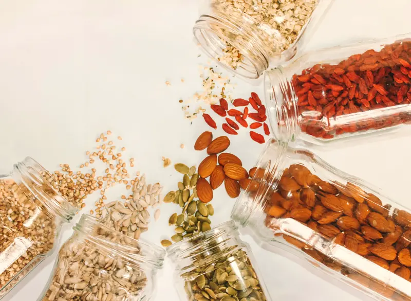 Barattoli di vetro con mandorle, semi e bacche di goji
